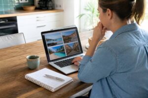 Persoon maakt een checklist tijdens het vergelijken van reisopties op een laptop